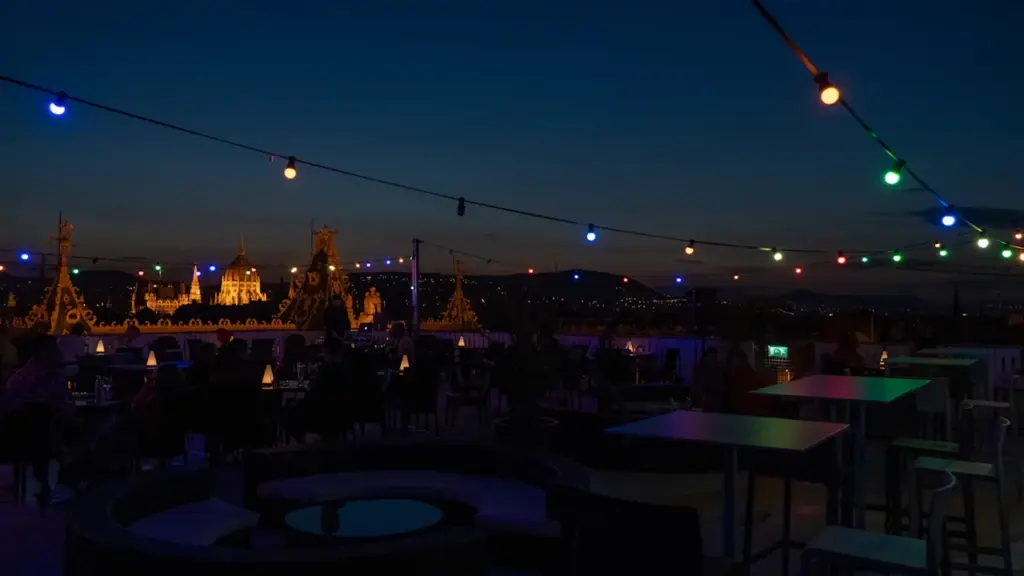Eine nächtliche Dachterrasse mit Lichterketten und einer weiten Aussicht über die Stadt.