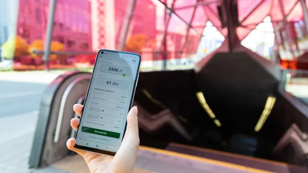 Eine Hand hält ein Smartphone mit einer Ticket-App vor einer modernen U-Bahn-Station.