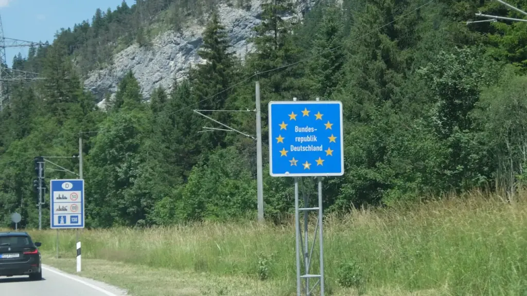 Ein offizielles Grenzschild der Europäischen Union an einer malerischen Bergstraße.