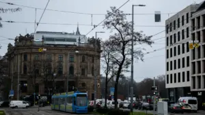 Eine blaue Straßenbahn fährt durch die Münchner Innenstadt mit historischen Gebäuden im Hintergrund.