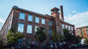 Die historische Baumwollspinnerei in Leipzig als kreativer Treffpunkt mit Backsteinfassade und Schornstein.