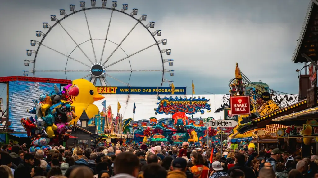 Buntes Volksfest mit Riesenrad und zahlreichen Besuchern bei bewölktem deutschem Himmel.