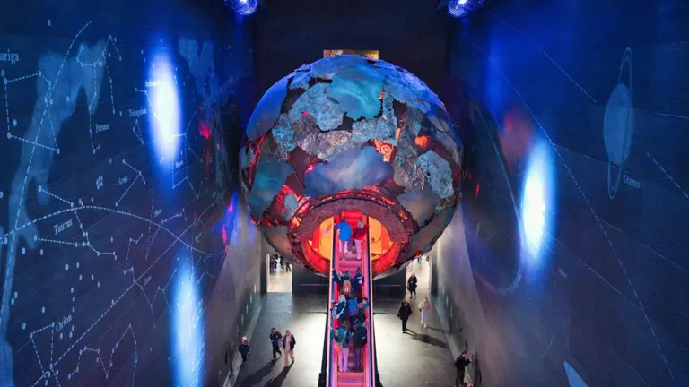 Große, leuchtende Globus-Installation in einer modernen Ausstellungshalle mit Rolltreppe im Deutschen Museum.