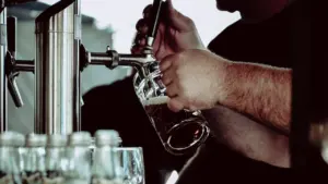 Bayerischer Bierausschank mit einer Person, die frisch gezapftes Bier in einen Krug füllt.