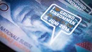 Detailaufnahme einer Schweizer Banknote mit einem Aufkleber zum bedingungslosen Grundeinkommen.