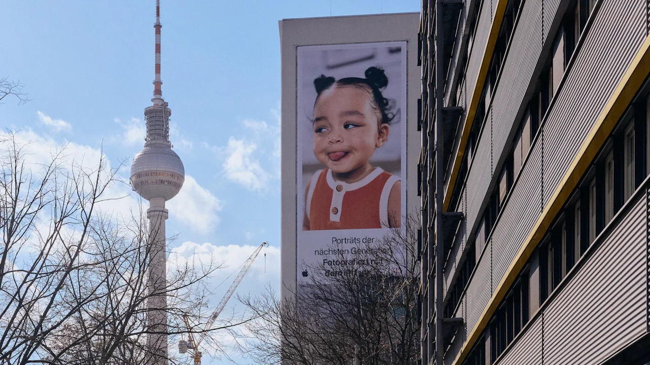Fernsehturm in Berlin mit einer Plakatwand, die ein lächelndes Kind zeigt.