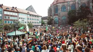 Eine große Menschenmenge versammelt sich auf einem öffentlichen Platz vor einem historischen Gebäude.