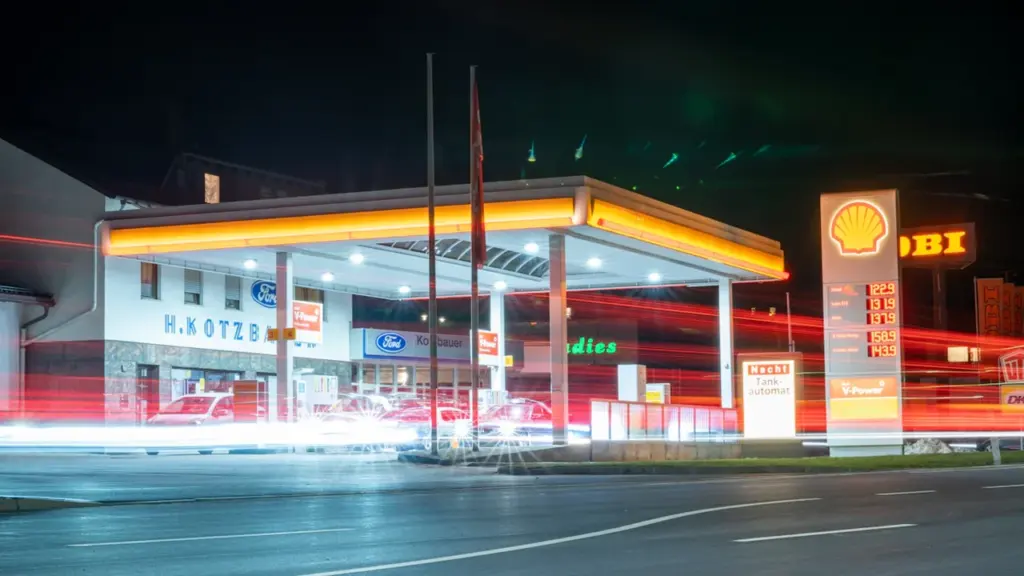 Eine deutsche Tankstelle bei Nacht mit gut sichtbaren Kraftstoffpreisen auf der Preisanzeige.