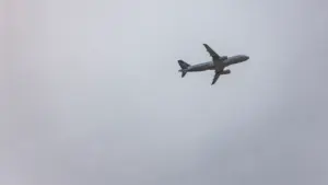 Ein einsames Flugzeug steigt vor einem trüben, grauen Himmel in die Höhe.