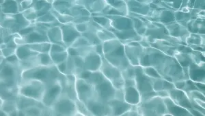 Klares, türkisblaues Wasser mit sanftem Lichtspiel an der Oberfläche eines Pools.