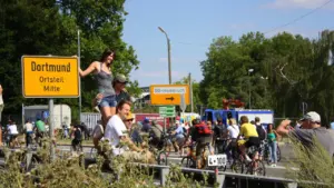 Menschen bei einer Veranstaltung am Ortsschild von Dortmund-Mitte im Sommer.