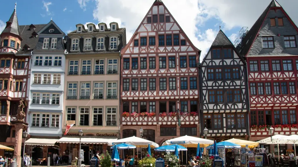 Historische Fachwerkhäuser auf dem Frankfurter Römerberg bei strahlendem Sonnenschein und blauem Himmel.