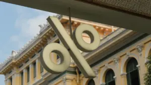 Ein großes, beleuchtetes Prozentzeichen hängt an einem historischen Gebäude in einer europäischen Stadt.