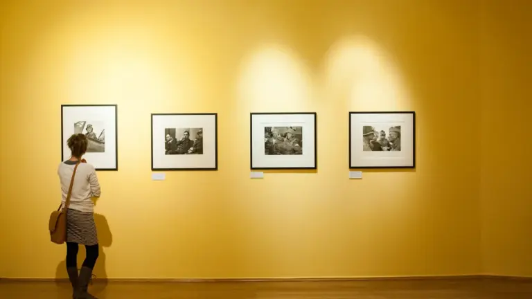 Besucherin betrachtet gerahmte Schwarz-Weiß-Fotografien an einer gelb gestrichenen Wand in einer Kunstgalerie.