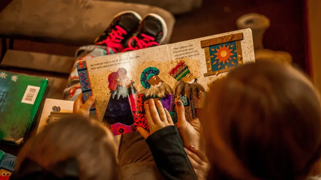 Zwei Kinder lesen gemeinsam ein farbenfrohes Bilderbuch auf einem bequemen Sofa.