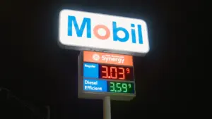 Leuchtendes Tankstellenschild mit aktuellen Kraftstoffpreisen bei Nacht an einer Tankstelle.