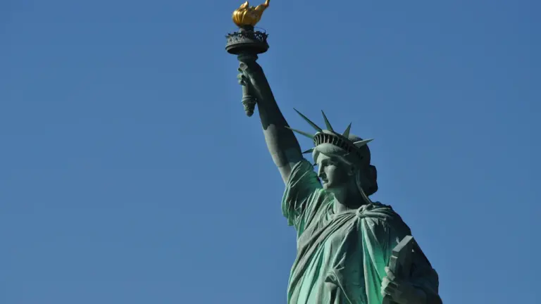 Die Freiheitsstatue vor einem klaren blauen Himmel bei hellem Tageslicht in New York.