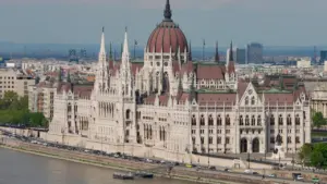 Das Budapester Parlamentsgebäude am Ufer der Donau bei hellem Tageslicht.